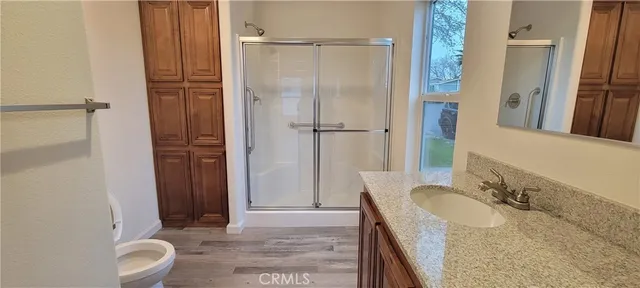 a bathroom with a granite countertop sink a mirror and shower