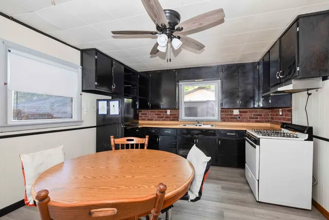 a kitchen with stainless steel appliances granite countertop a sink a stove a refrigerator a microwave oven with white cabinets and wooden floor