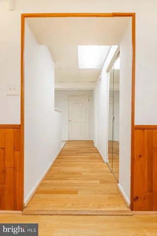a view of a hallway with wooden floor and a bathroom