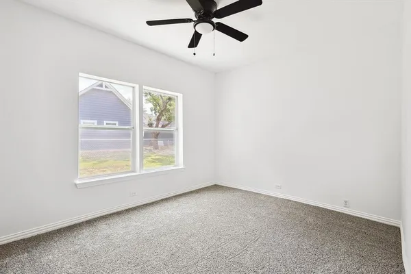 an empty room with a window and a fan