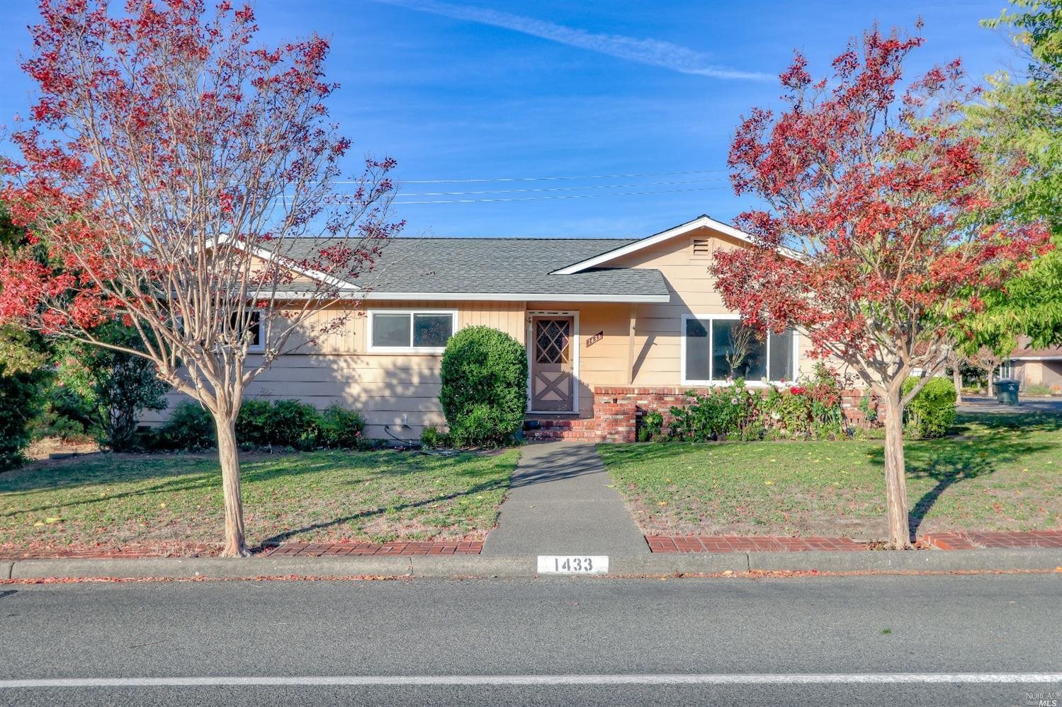 a view of a white house next to a yard with big trees