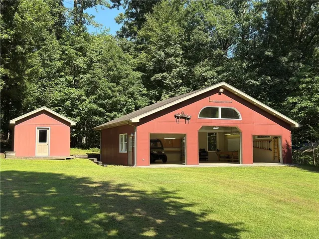 a view of a yard in front of a house with plants and large tree