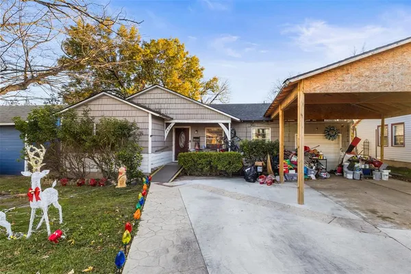 a view of a house with a small yard and a large tree