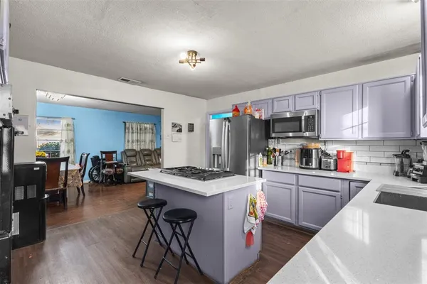 a kitchen with kitchen island a stove a sink a refrigerator dining table and chairs