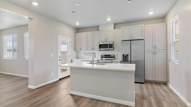 82 Provo River Road, Unit 251 Saratoga Springs, UT 84045 - Photo 8 of 32 Modern kitchen featuring a central island, light-toned cabinetry, stainless steel appliances, and wood-finish flooring