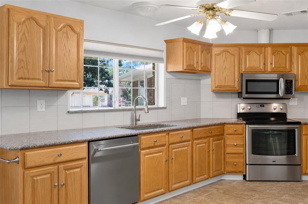 1612 Whitemound Road Sherman, TX 75090 - Photo 5 of 28 Kitchen featuring wood cabinetry, stainless steel appliances, granite countertops, and a tile backsplash