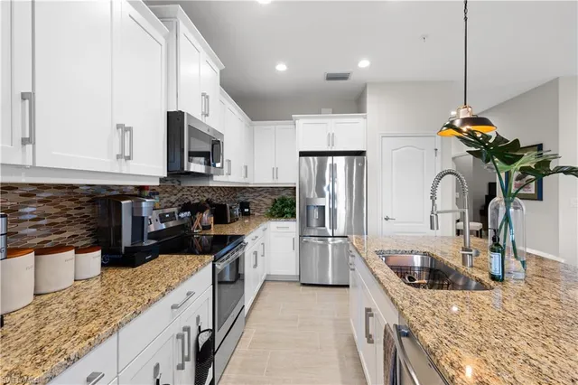 a kitchen with stainless steel appliances granite countertop a sink a stove and a refrigerator