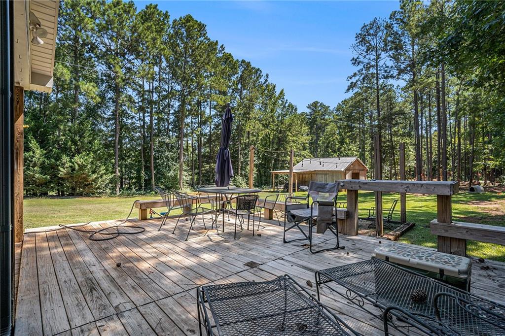23 Erskine Road Monticello, GA 31064 - Photo 29 of 38 a view of a patio with table and chairs under an umbrella with large trees