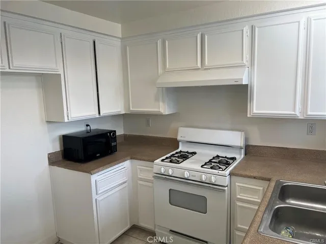 a kitchen with granite countertop white cabinets and white appliances