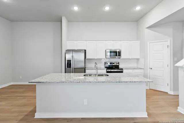 a large kitchen with granite countertop a sink and white cabinets