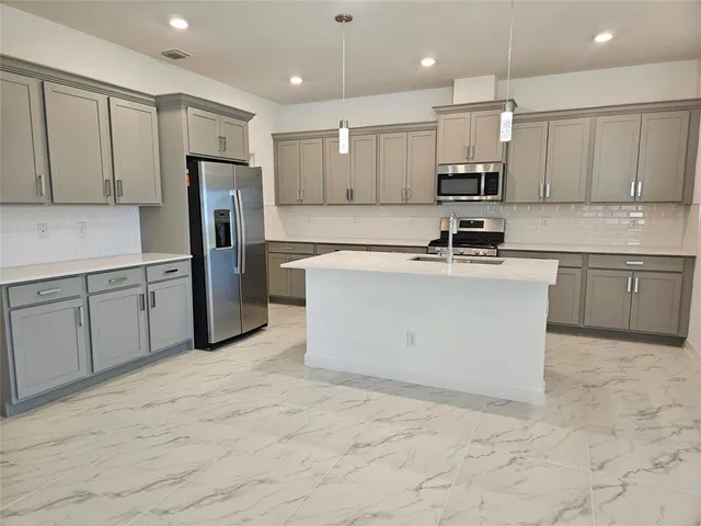 a kitchen with stainless steel appliances granite countertop a stove top oven a refrigerator a sink and white cabinets