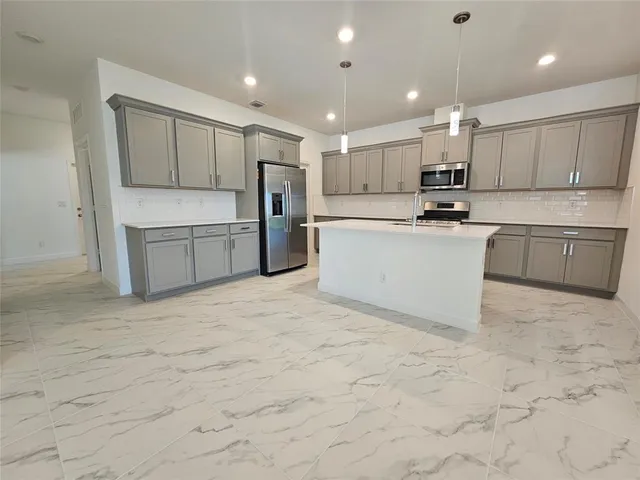 a large white kitchen with kitchen island a sink a center island stainless steel appliances and a cabinets