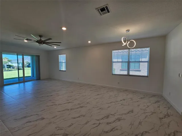 an empty room with windows and ceiling fan