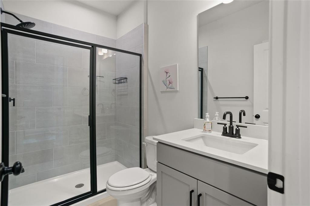 764 Clifftop Crossing Southwest Powder Springs, GA 30127 - Photo 21 of 38 a bathroom with a sink a mirror a toilet and shower