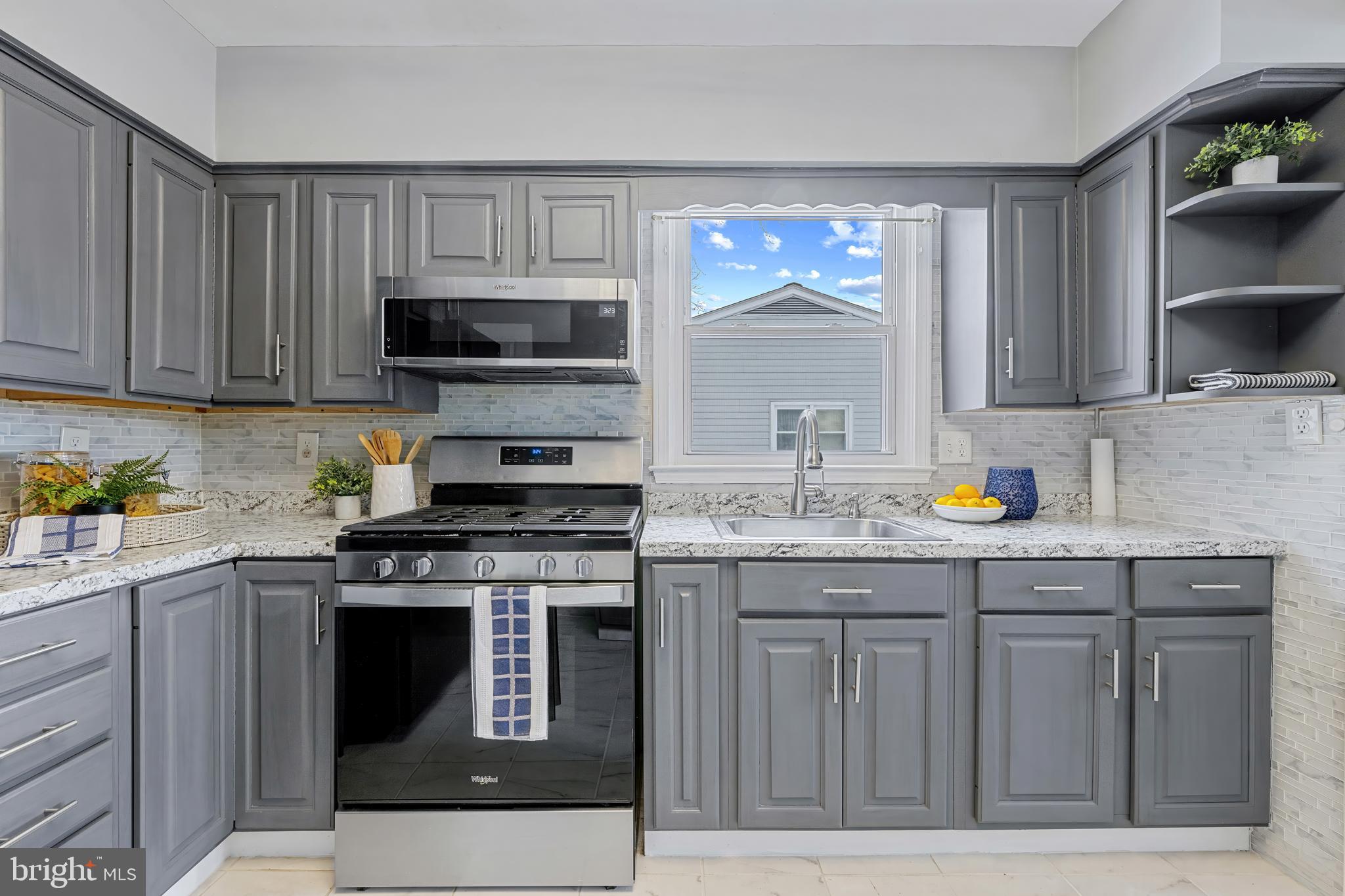 911 Homberg Avenue Baltimore, MD 21221 - Photo 9 of 28 a kitchen with granite countertop a stove top oven a sink dishwasher and cabinets with wooden floor