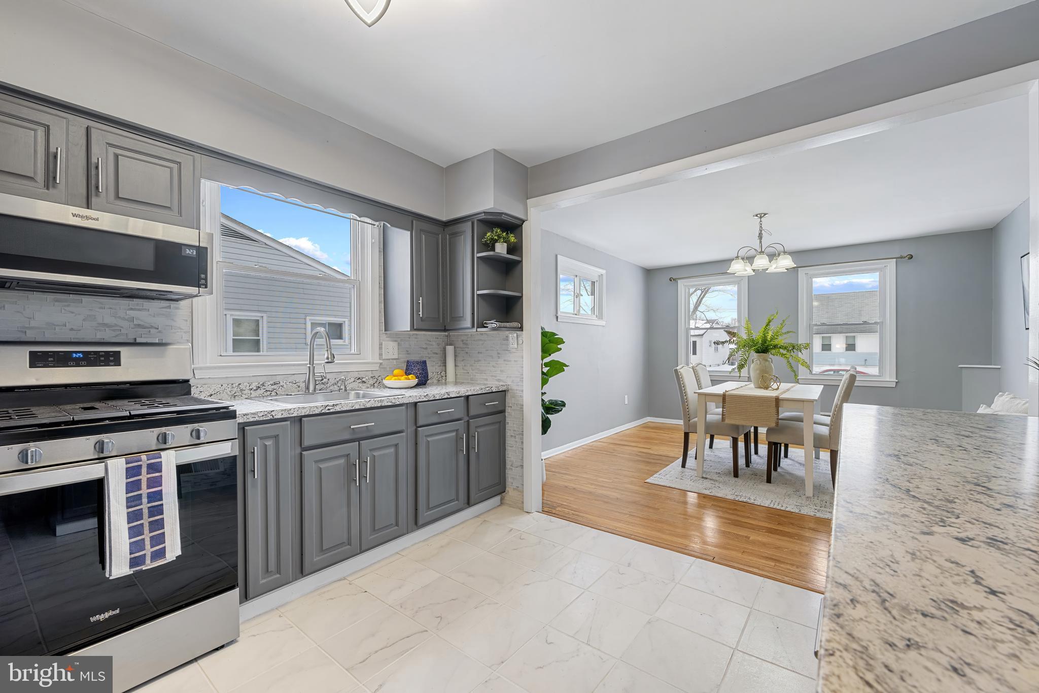 911 Homberg Avenue Baltimore, MD 21221 - Photo 10 of 28 a kitchen with stainless steel appliances granite countertop a stove top oven a sink dishwasher a dining table and chairs with wooden floor