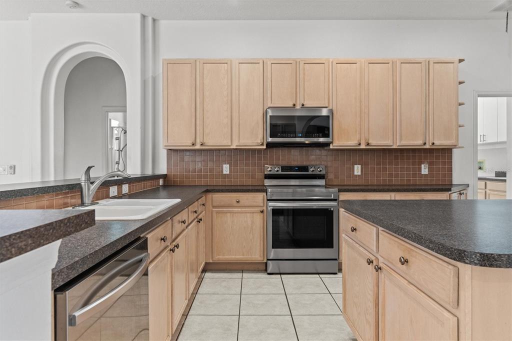 20744 Sheldon Street Orlando, FL 32833 - Photo 11 of 50 a kitchen with stainless steel appliances granite countertop a sink a stove a microwave and cabinets