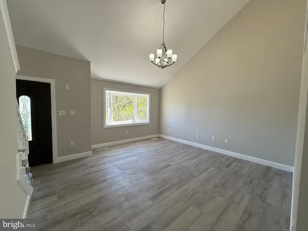 an empty room with wooden floor chandelier