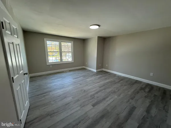 an empty room with wooden floor and a window