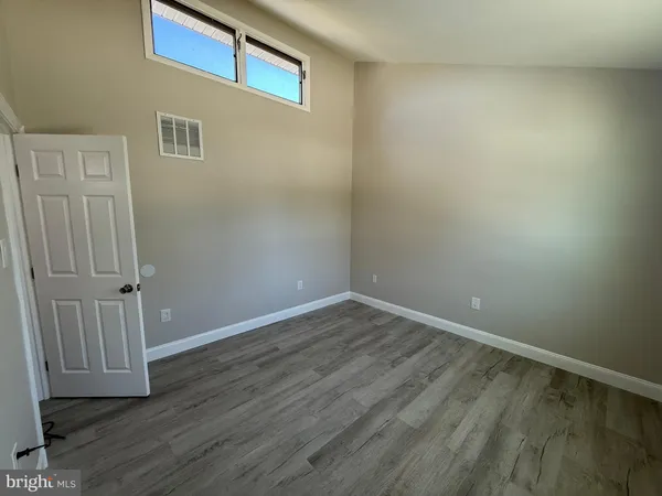 a view of an empty room with wooden floor and entryway