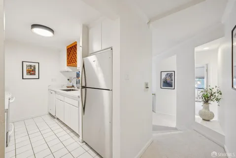a white refrigerator freezer sitting in a kitchen with white cabinets