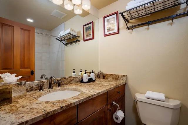 a bathroom with a granite countertop sink a toilet and a mirror