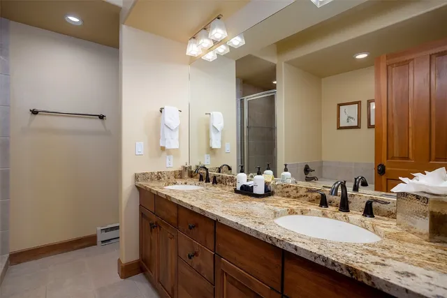 a bathroom with a granite countertop double vanity sink and a mirror