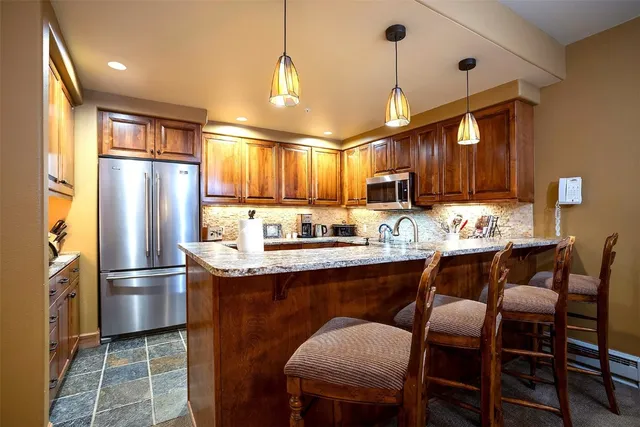 a kitchen with stainless steel appliances granite countertop a sink refrigerator dining table and chairs