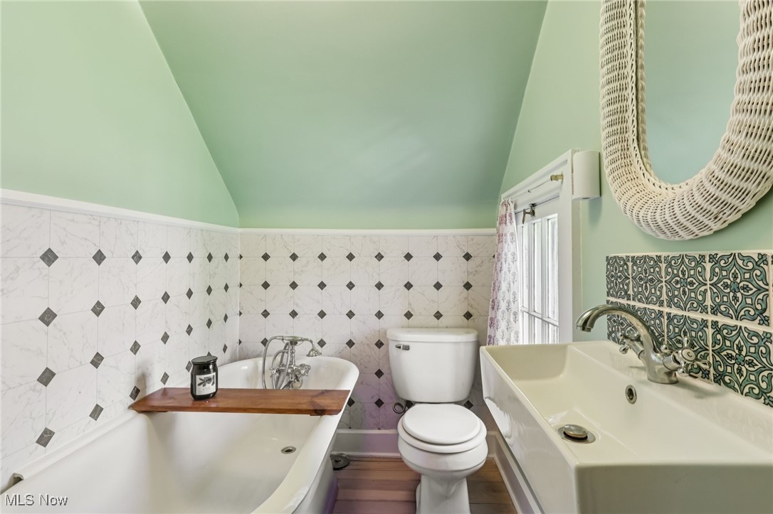 922 Mayfair Road Akron, OH 44303 - Photo 29 of 39 Full bathroom featuring lofted ceiling, a freestanding tub, tile walls, a wainscoted wall, and wood finished floors