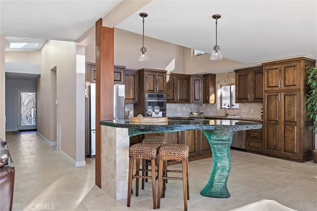 a kitchen with stainless steel appliances kitchen island granite countertop a table chairs and a refrigerator