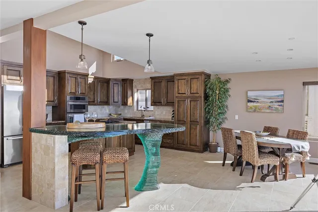 a kitchen with kitchen island a dining table chairs stainless steel appliances and cabinets