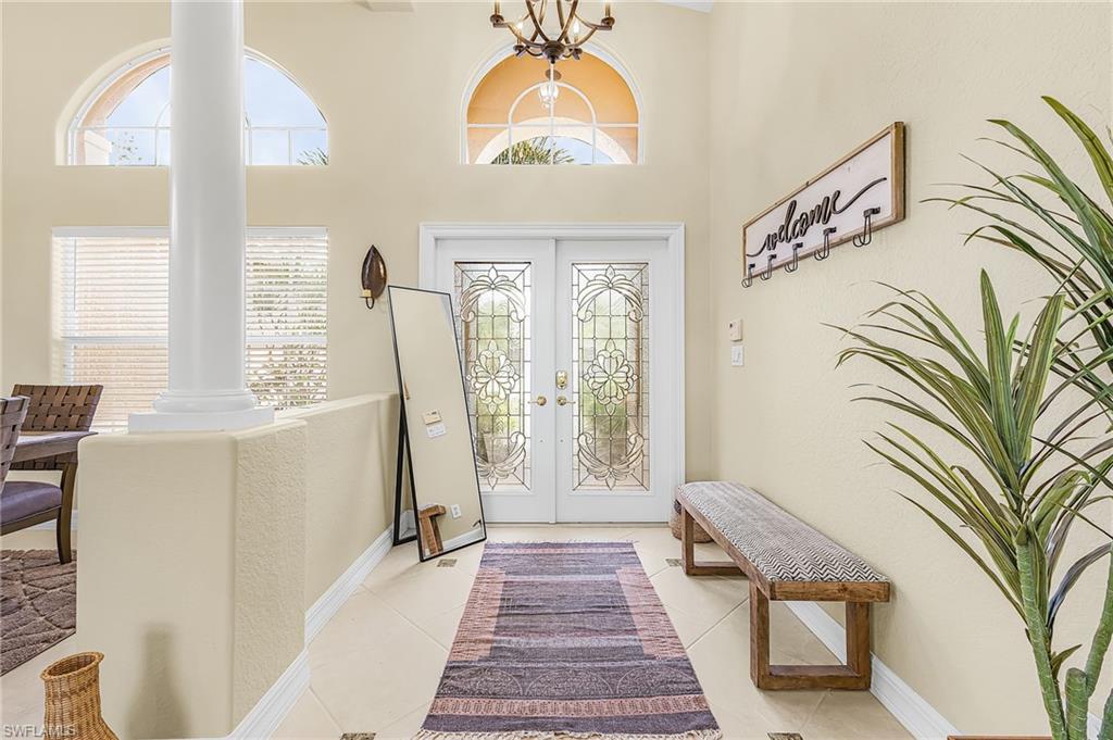 1415 Princess Sabal Point Naples, FL 34119 - Photo 4 of 42 Bright foyer featuring dual glass-paneled doors with decorative muntins, arched transom windows, light-filled spaces with crown molding, and polished tile flooring