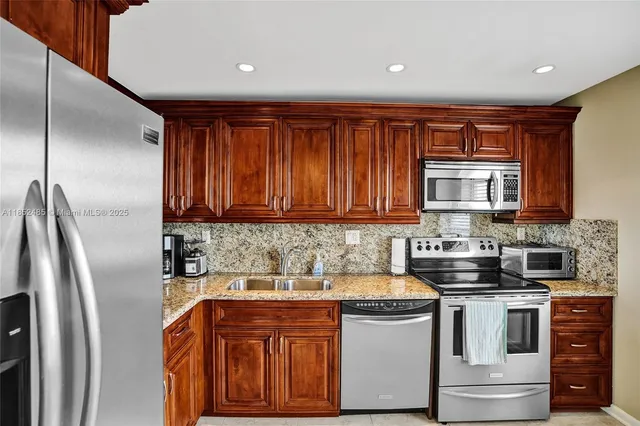 a kitchen with stainless steel appliances granite countertop a refrigerator sink and stove