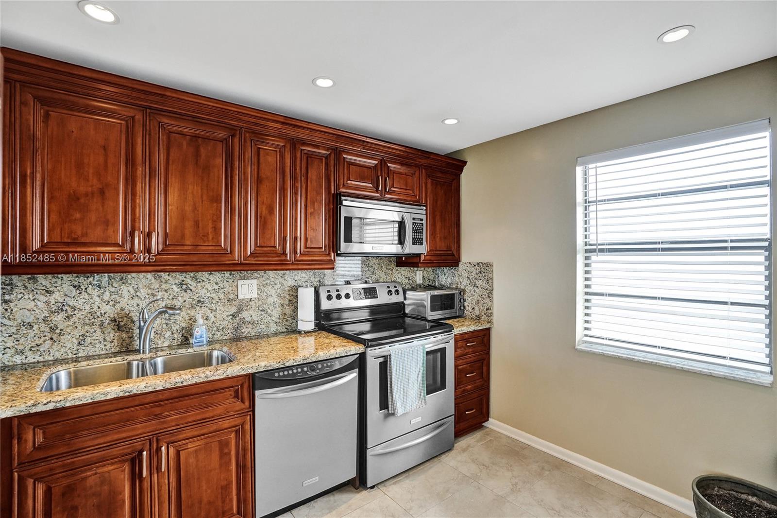 1401 North Riverside Drive, Unit 1005 Pompano Beach, FL 33062 - Photo 15 of 49 a kitchen with stainless steel appliances granite countertop a sink stove and cabinets