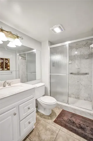 a bathroom with a shower sink vanity mirror and toilet