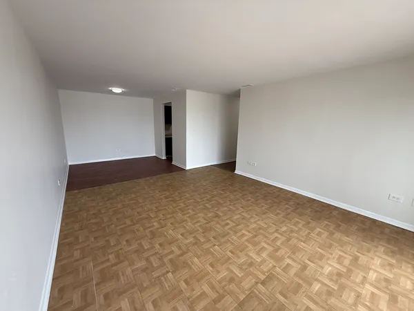 a view of an empty room with wooden floor and a ceiling fan