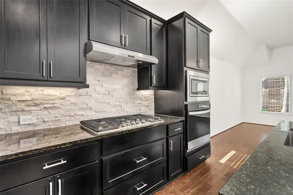 a kitchen with granite countertop wooden cabinets and stainless steel appliances
