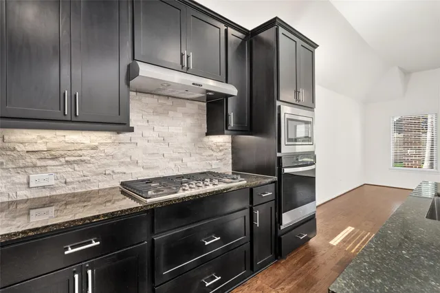 a kitchen with granite countertop wooden cabinets and stainless steel appliances