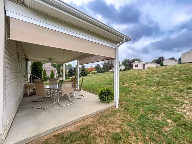 a view of a patio with table and chairs under an umbrella next to a yard