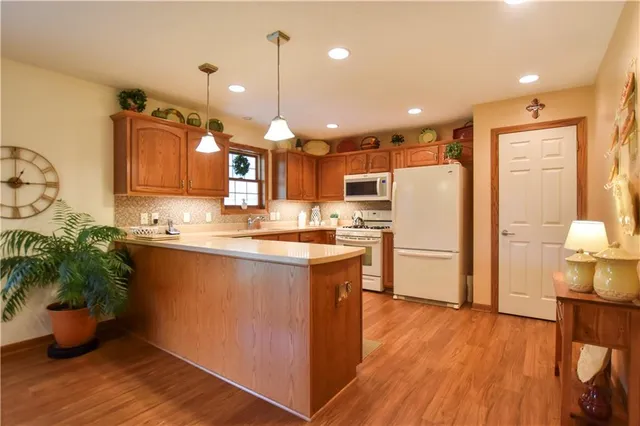 a kitchen with stainless steel appliances granite countertop a refrigerator a sink dishwasher a oven and a dining table with wooden floor