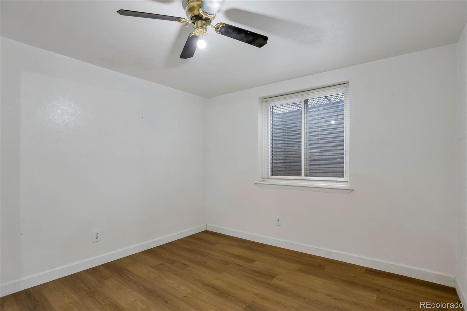 4437 Durham Court Denver, CO 80239 - Photo 12 of 15 a view of an empty room with a window and wooden floor