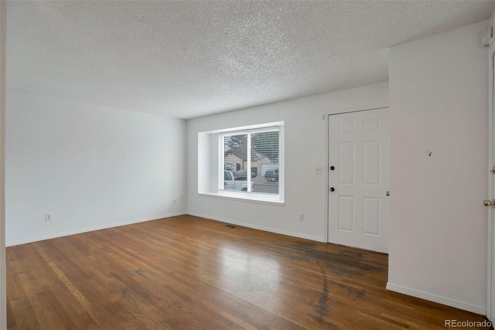 4437 Durham Court Denver, CO 80239 - Photo 3 of 15 a view of an empty room with wooden floor and a window