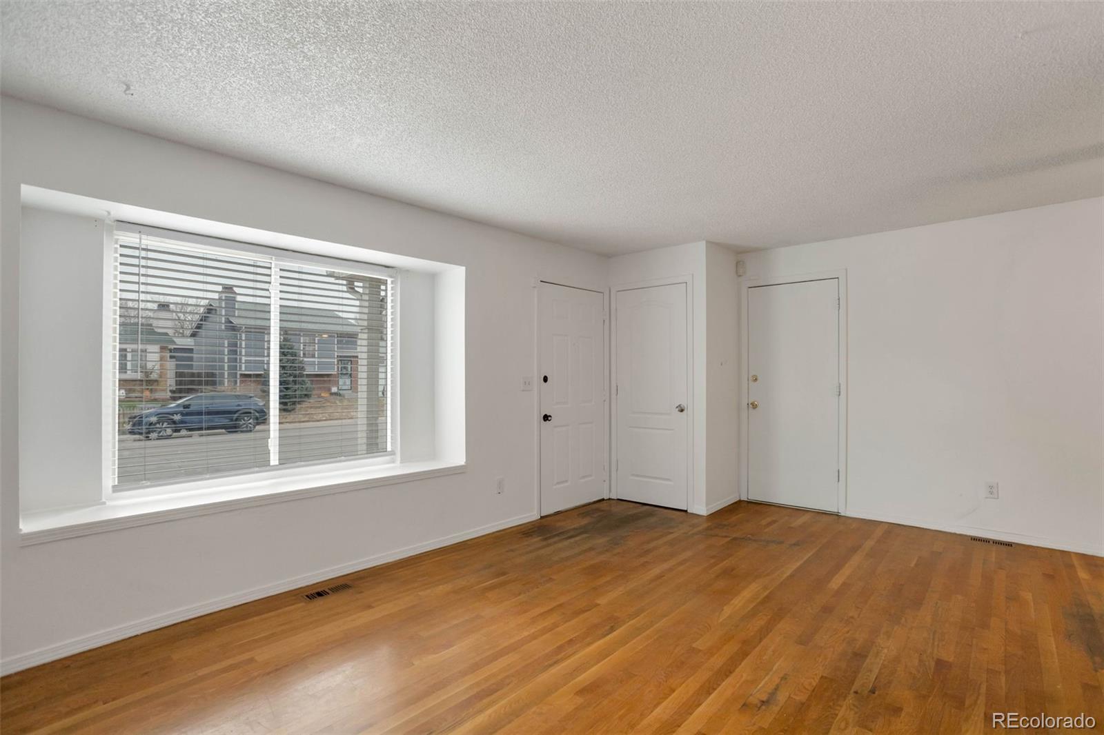4437 Durham Court Denver, CO 80239 - Photo 4 of 15 a view of empty room with wooden floor and fan
