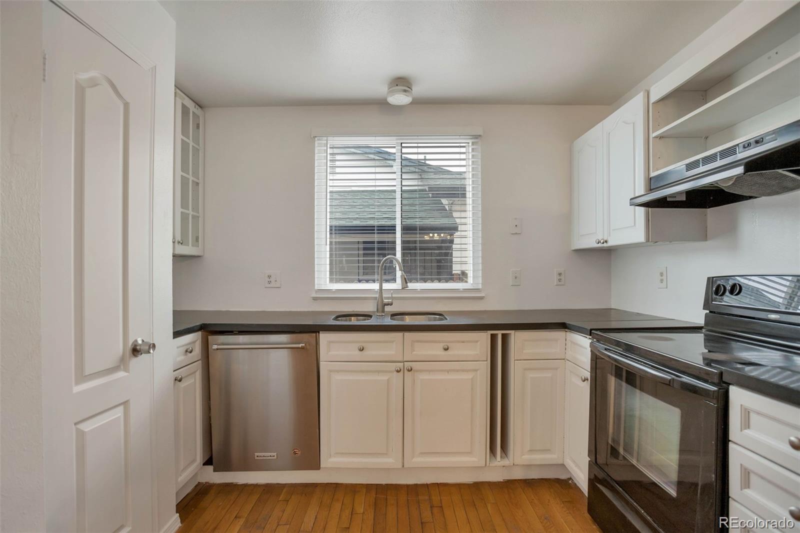 4437 Durham Court Denver, CO 80239 - Photo 7 of 15 a kitchen with granite countertop white cabinets and white appliances
