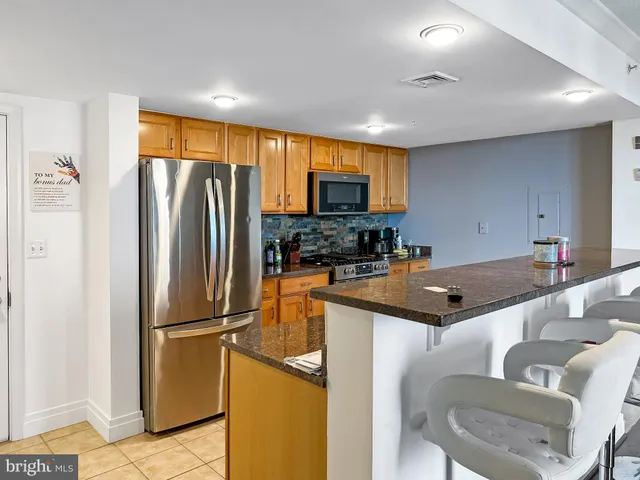 a kitchen with stainless steel appliances granite countertop a refrigerator a stove a sink a dining table and chairs