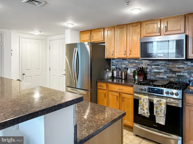 a kitchen with stainless steel appliances granite countertop a stove a refrigerator and a sink