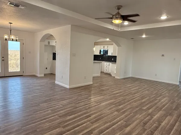 an empty room with wooden floor and chandelier