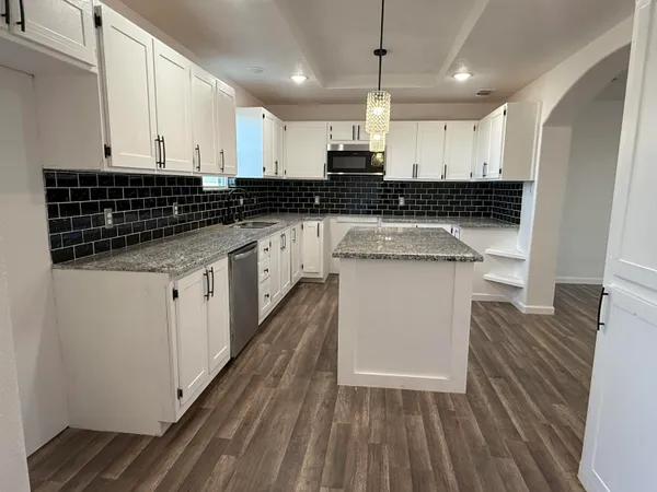 a kitchen with stainless steel appliances granite countertop a stove a sink and white cabinets