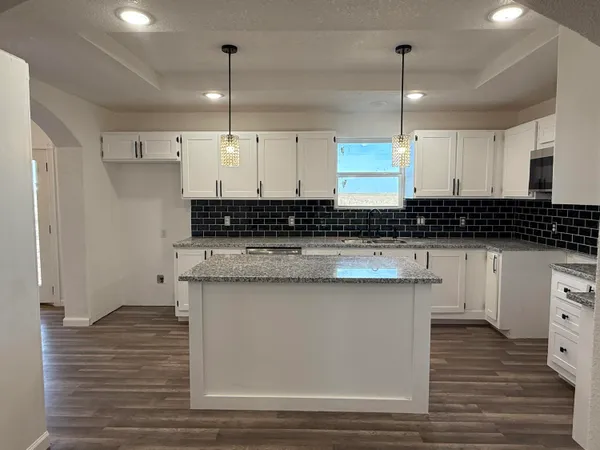 a kitchen with stainless steel appliances granite countertop a sink a stove and a wooden floors