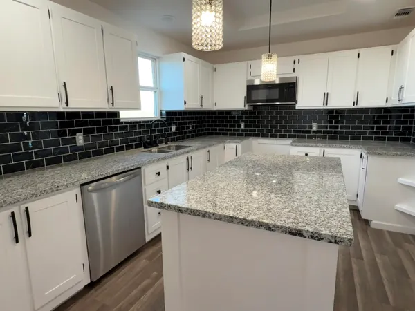 a kitchen with granite countertop a sink a stove and cabinets